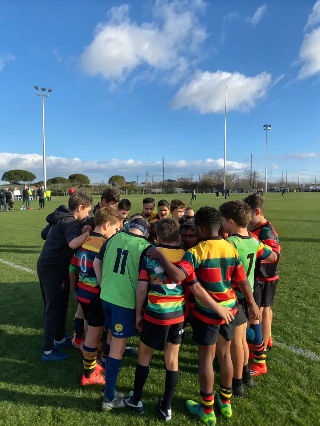 A vibrant photograph capturing young children participating in a rugby training session at Haguenau Rugby Club, focusing on teamwork and basic skills, set against a backdrop of the club's field and facilities.